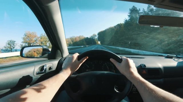 Driver holds both hands on steering wheel as he drives his car
