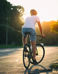 Printed kitchen splashbacks Bicycles The young guy in casual clothes is cycling on the road in the evening city