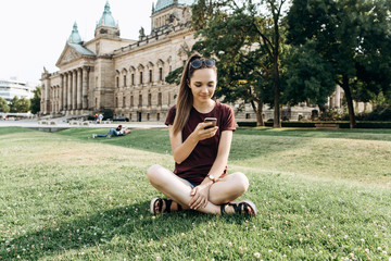 A girl or student rests on grass in Leipzig in a park or on the street in a free style and uses a...