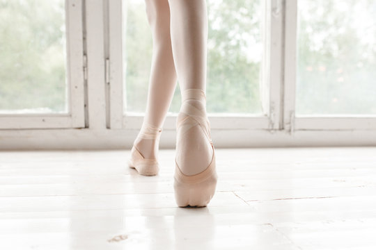 Legs and slippers of classical ballet dancers rehearsing on a light background