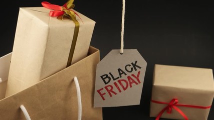 Shopping bag with two gift boxes and  promotional sign of black Friday on the black background