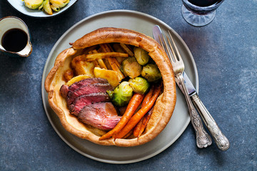 Roast dinner with beef, carrots, brussel sprouts in giant yorkshire pudding