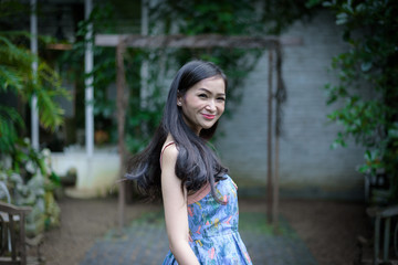 Naklejka premium Asian pretty girl has relaxing with happy and smiling at Little Tree Garden cafe, Nakhon Pathom province, Thailand in the morning.