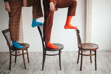 Crop people in bright socks on chairs