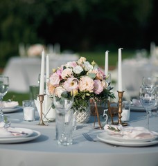 elegant table setup alongside with some candles in blue pastels for wedding and a number 5 sign