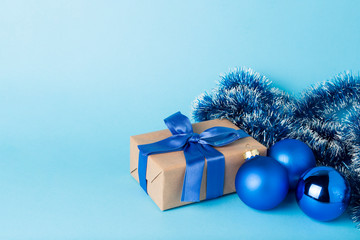 Fototapeta na wymiar Gift box with blue ribbon, Christmas decorations on a blue background. Minimalism. Concept of a gift for loved ones