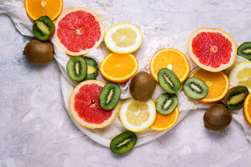 Fresh Tropical Fruits, Grapefruit, Lemon, Orange, Kiwi on a Light Stone Background. Copy space and a top view