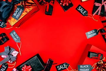 Goods and presents in black and red covers with black sale labels on red background. Sale and discount in shopping mall, store and shops in black friday holiday concept.