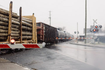 freight train carrying lumber at a crossing in the snow