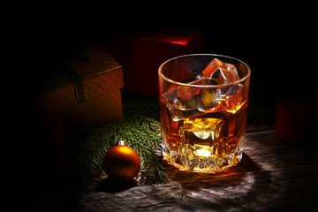 Glass with cognac or whiskey, Christmas balls and candles. New Year's tree, balls and glass with alcohol.