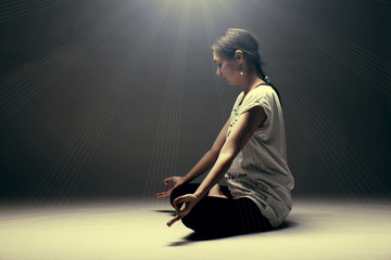 Fototapeta na wymiar Yoga girl meditating. Young female doing exercise on gray background. Toned photo