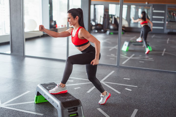 Smiling sportswoman working out with step platform