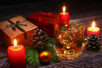 Glass with cognac or whiskey, Christmas balls and candles. New Year's tree, balls and glass with alcohol.