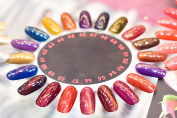 Different colorful nails polish manicure palette Background. Samples of nail varnishes. False...