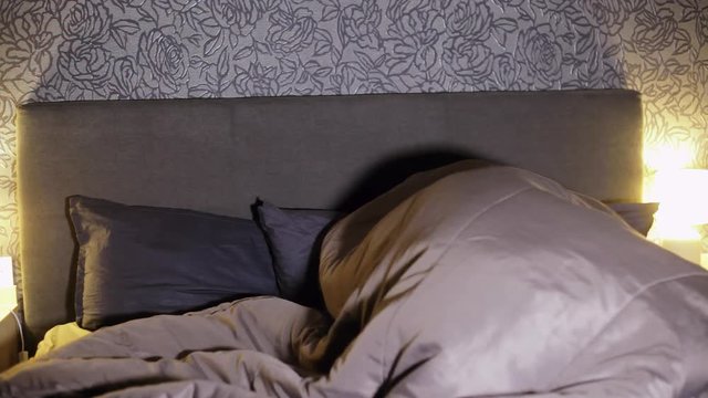 Young couple frolicking under the blanket in the bedroom in the evening. Lovers having sex