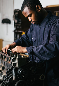 Mechanic fixing an engine for a head gasket repair in a garage.