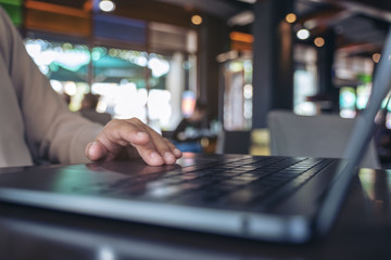 Closeup image of hands using and touching on laptop touchpad on wooden table