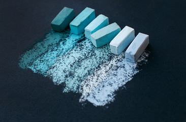 Assorted blue soft pastel chalks and it's swatches on black paper