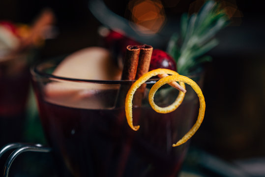 Close up of orange rind and a cinnamon stick in a glass of mulled wine
