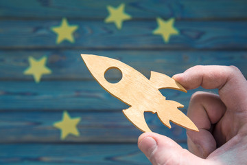 The hand of a businessman launches a rocket to five stars on a blue background. Business concept idea, success and achievement, work. Winner, career ladder.