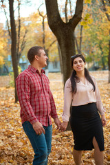 Happy couple is walking in autumn city park. Bright yellow trees.