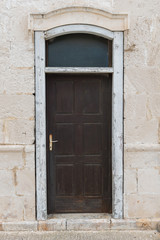 Fototapeta na wymiar Old brown wooden doors with old stone wall around. Old rustic doors. Stone frame.