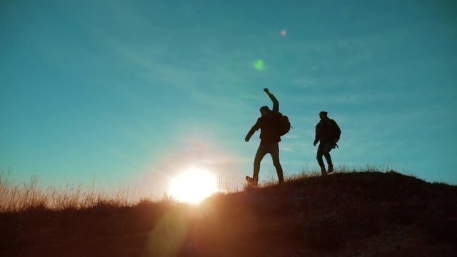 teamwork run jump throw backpacks happiness joy victory success. Two hikers enjoying sunrise walking from top of a mountain and dog. Two hikers with backpacks climbing a peak on cloud sky background