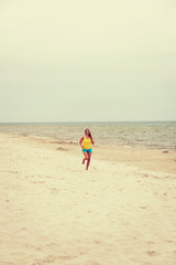 Obraz premium Young woman running on the beach