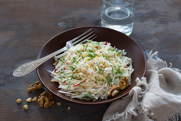 Vegetarian Jerusalem artichoke (topinambour) salad with apple, walnut and greens on a dark wooden background. healthy diet food