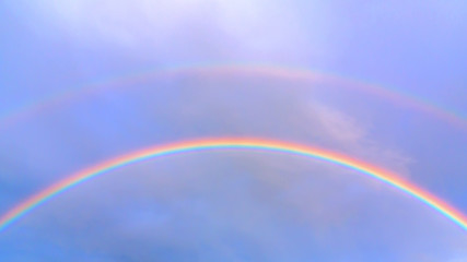 Double rainbow in the blue sky on a summer day
