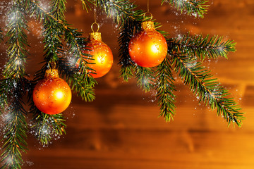 Orange Christmas ornaments on spruce branches on the background of a wooden wall. New Year or Christmas background