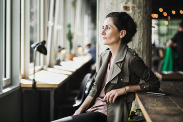 Short dark haired woman sitting in a cafe waiting