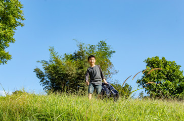 Asian boy holding bag Background grass and trees