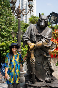 Thai woman posing for take photo with twelve chinese zodiac Dog angel statue at Wong Tai Sin Temple in Hong Kong, China