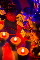 Merry Cristmas. Toy houses and candlelight. Christmas decorations on blurred background. Festive evening. Spruce branches and Christmas toys with bokeh. Copy space