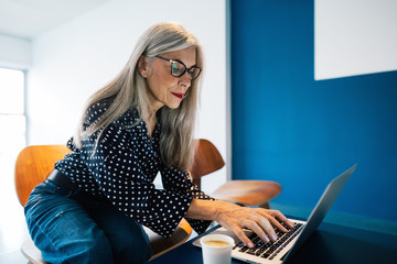 Senior businesswoman working on laptop at office.