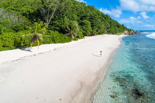 A woman strolling along Anse Fourmis beach. La Digue, Seychelles, Africa