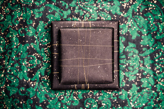 Two gifts in black wrapping on funky green background