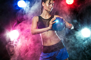 Beautiful fitness woman athlete and bodybuilder with perfect body doing trainging with medicine ball background.