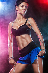 Obraz premium Fit sports woman athlete. Workout with bands or expander in gym with colorful bright blue and red lights.