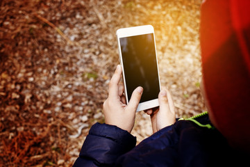 The child spends personal time in nature doing photographing the environment. Little nature Explorer taking pictures with a smart phone.