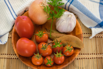 cherry tomato, lettuce, onion, parsley, garlic and bay leaf in a wooden plate