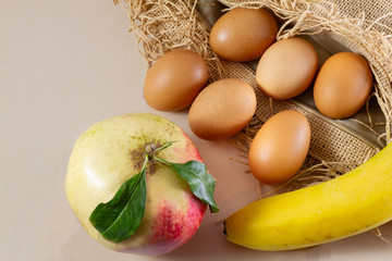 Six eggs one pomegrenate and one banana on sackcloth (burlap) and white background- traditional organic food concept demonstration
