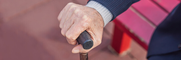 Old man hand holding walking stick outdoor BANNER, LONG FORMAT