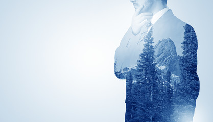 Young businessman standing and meditate with trees on the background 