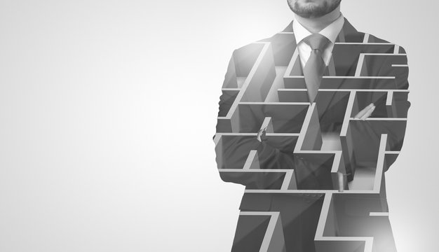 Young businessman in suit standing with maze graphic 
