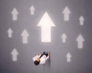 Young contemplating businessman stands in front of white arrows