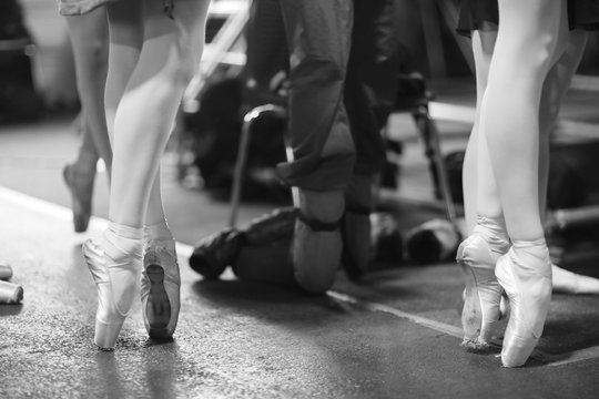 Legs of ballerinas standing on pointe shoes at the rehearsal of the performance