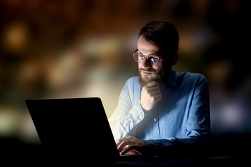 Young handsome businessman working late at night in the office