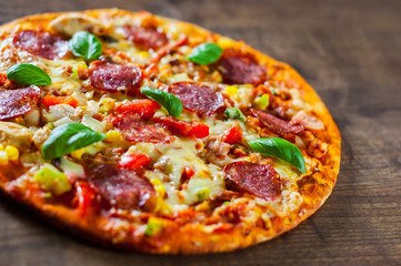Pizza with Chicken meat, Mozzarella cheese, pepperoni, tomato, vegetables, salami. Italian pizza on wooden background